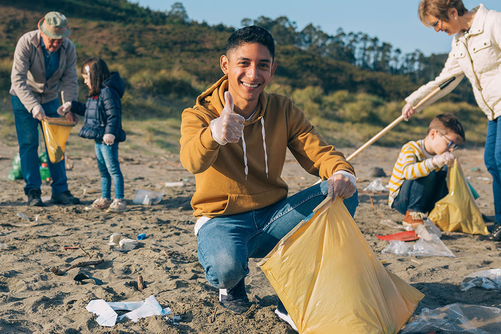 young man picking up rubbish with group of volunteers