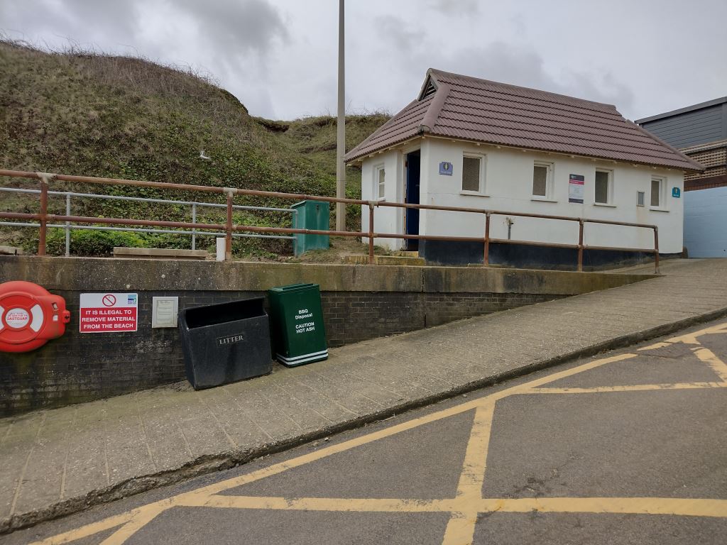 Green BBQ disposal bin outside chalets in West Runton